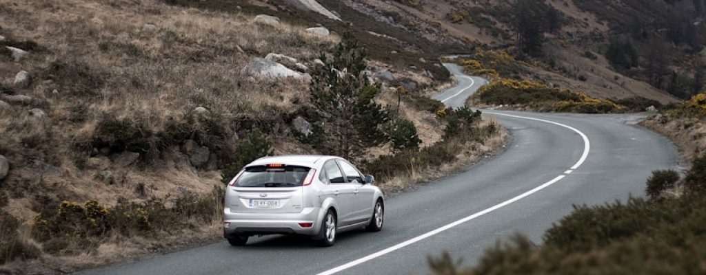 photography of moving silver sedan on road